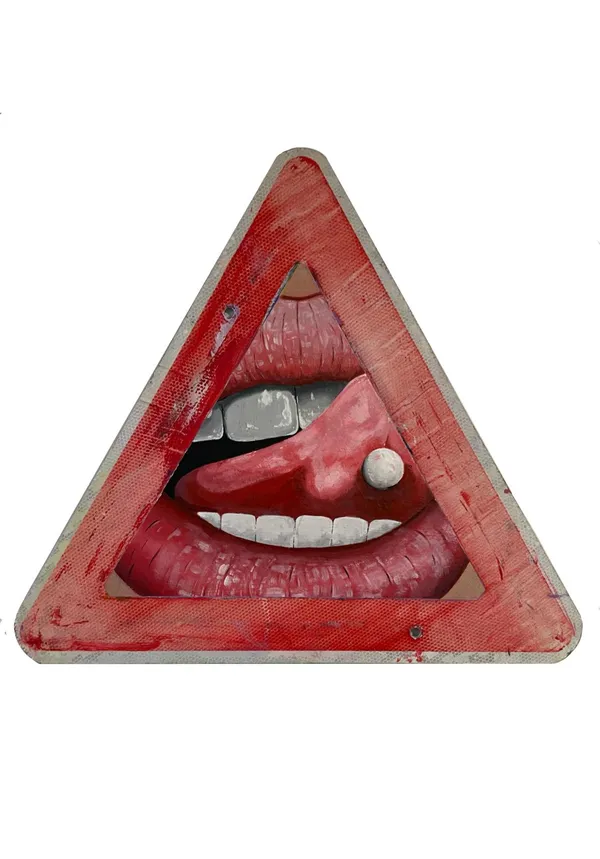 A weathered triangular red road sign with its centre cut away and filled by a painted open mouth — upper and lower teeth, and a tongue pushed out with a white pill resting on it.
